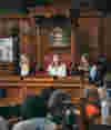 A panel discussion takes place in a room at Oxford Town Hall adorned with a coat of arms, where the audience listens attentively. 