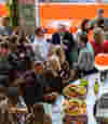 Group of people surrounding a bar with name tags drinking food and alcohol