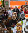Group of people surrounding a bar with name tags drinking food and alcohol