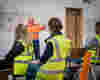 Workers wearing high-visibility vests listening during a workplace session in Woolcool, a certified B Corp. With papers of hand drawn sustainability goals at the background.
