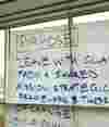 A large piece of paper attached to a window displaying handwritings that says: "Purpose: Leave with clarity from a shared mission, strategic framework, and theory of change."