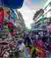 A vibrant, crowded outdoor market in Kariakoo, with shoppers walking down a narrow street.